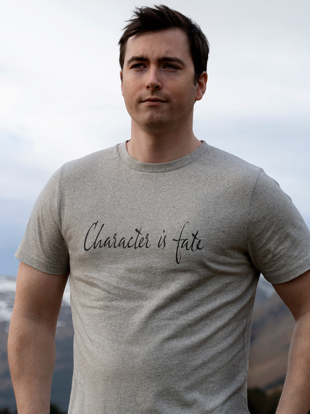 man wearing grey recycled cotton t-shirt with Character is Fate printed slogan